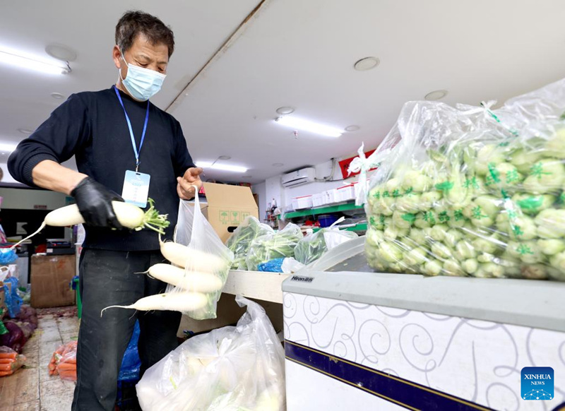 Mhudumu akifungasha mboga kwenye mifuko kwa ajili ya oda za mtandaoni katika duka kubwa huko Shanghai, Mashariki mwa China, Aprili 10, 2022. (Xinhua/Chen Jianli)