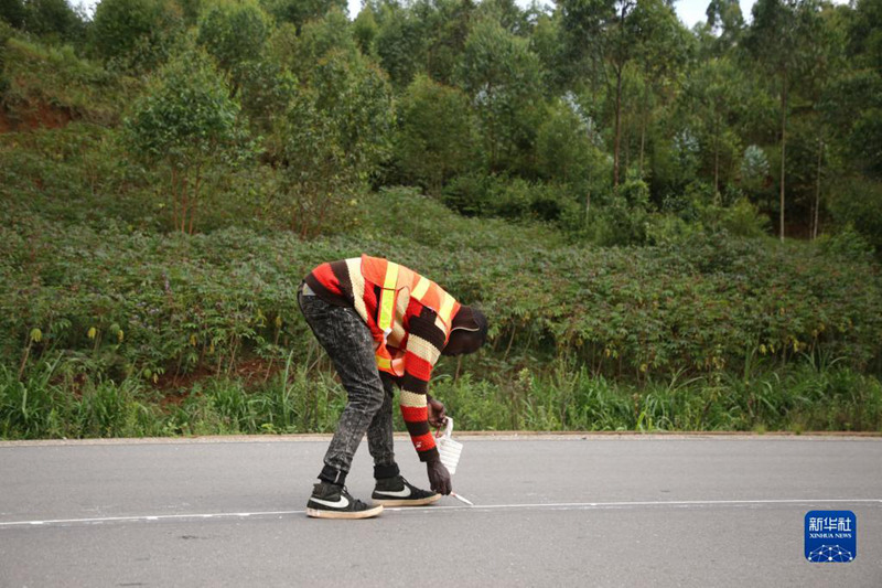 Tarehe 21, Aprili, mfanyakazi akichora mstari wa alama kwenye barabara ya Huye inayoeleka Kibeho, Rwanda. (Picha/Xinhua)