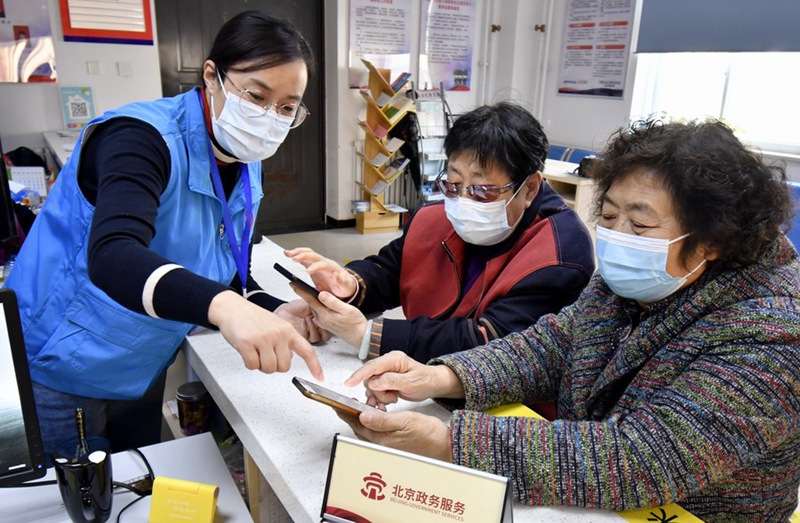 Mhudumu wa kujitolea akiwasaidia wazee kutumia APP ya malipo ya mtandaoni kwenye moja ya makazi katika Eneo la Fengtai la  Beijing, Mji Mkuu wa China, Novemba 12, 2021. (Xinhua/Li Xin)