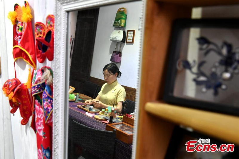 Msichana anayejikita katika kufuma vifungo vya nguo vya jadi vya China