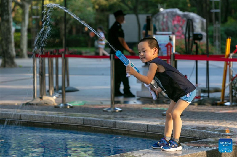Mtoto akichezea mdori wa bunduki ya maji huku kukiwa na joto kali kwenye bustani katika Eneo la Xuhui, mjini Shanghai, Mashariki mwa China Julai 10, 2022. Shanghai Jumapili ilitangaza tahadhari nyekundu ya halijoto ya juu, huku joto kali ikiukumba mji huo. China ina mfumo wa tahadhari ya hali ya hewa wenye hatua nne, unaowakilishwa kwa alama za rangi, na rangi nyekundu inaashilia tahadhari kali zaidi, ikifuatiwa na machungwa, manjano na buluu. (Xinhua/Wang Xiang)