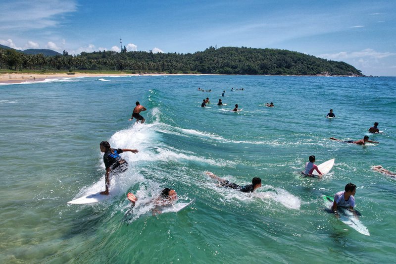 Watu wateleza kwenye mawimbi na kufurahia mandhari nzuri ya Wanning, Hainan