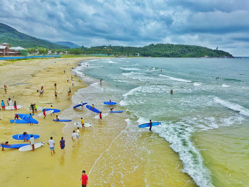 Watu wateleza kwenye mawimbi na kufurahia mandhari nzuri ya Wanning, Hainan