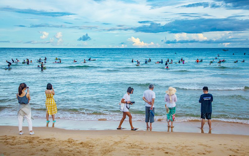 Watu wateleza kwenye mawimbi na kufurahia mandhari nzuri ya Wanning, Hainan