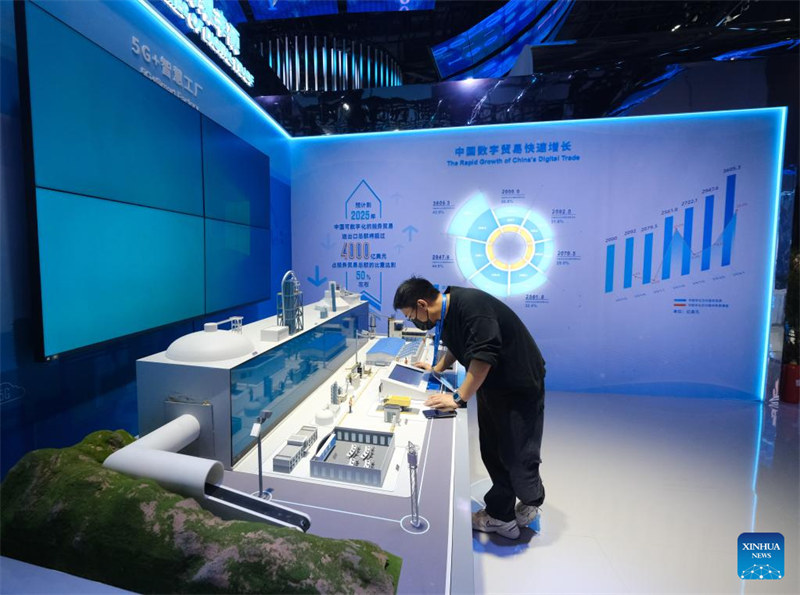Mfanyakazi akiangalia mfano wa Kiwanda kinachotumia teknolojia ya akili bandia ya 5G+ kwenye Maonyesho ya Kwanza ya Kimataifa ya Biashara ya Kidigitali huko Hangzhou, Mkoa wa Zhejiang nchini China, Desemba 11, 2022. Maonyesho hayo ya siku 4 yameanza hapa Jumapili. Takriban kampuni 800 zinazoongoza za biashara ya kidijitali kutoka China na nje ya nchi hiyo zitaonyesha bidhaa na teknolojia zao mpya kwenye maonyesho hayo. (Xinhua/Xu Yu)