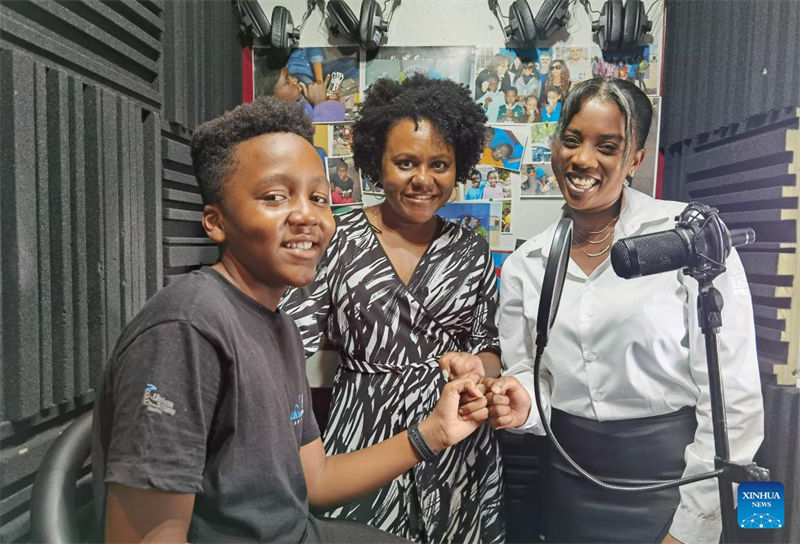 Mathew Haipare (kushoto) akipozi ili kupigwa picha pamoja na mama yake (kati) na Elizabeth Hamurenge, mratibu wa studio huko Windhoek, Namibia, Februari 13, 2023. (Picha na Ndalimpinga Iita/Xinhua)