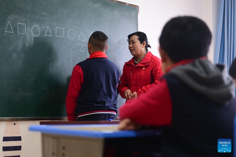 Cheng Zhifang (wa katikati) akimfundisha mtoto mwenye tatizo la usonji kufanya mazoezi ya utambuzi kwenye kituo cha huduma kwa watoto wenye mahitaji maalum  cha Starlight mjini Xining, Mkoa wa Qinghai wa Kaskazini Magharibi mwa China tarehe 30, Machi, 2023.