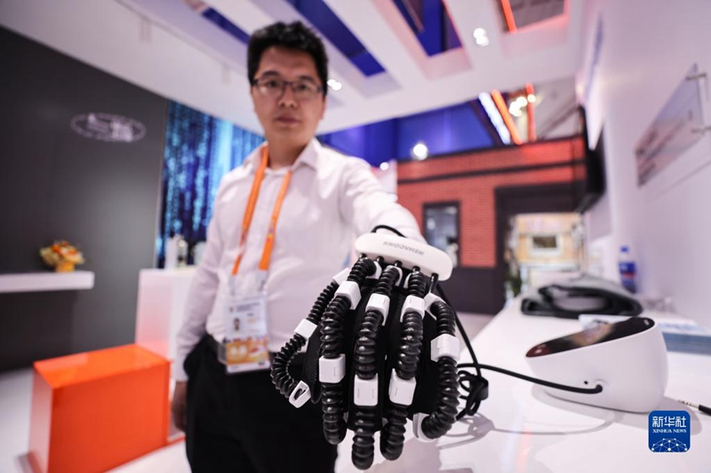 Mfanyakazi wa kampuni inayoshiriki kwenye maonesho ya CICPE akionesha roboti ya kufanya mazoezi ya mikono kwenye banda la Mji wa Shanghai Tarehe 11, Aprili. 