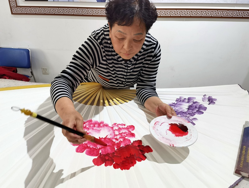 Mchoraji akichora picha ya maua ya peony kwenye  kipepeo cha kijadi cha China katika Kijiji cha Pingle Aprili 11, 2023. (Picha na Mwandishi wa People's Daily Online, Du Mingming)