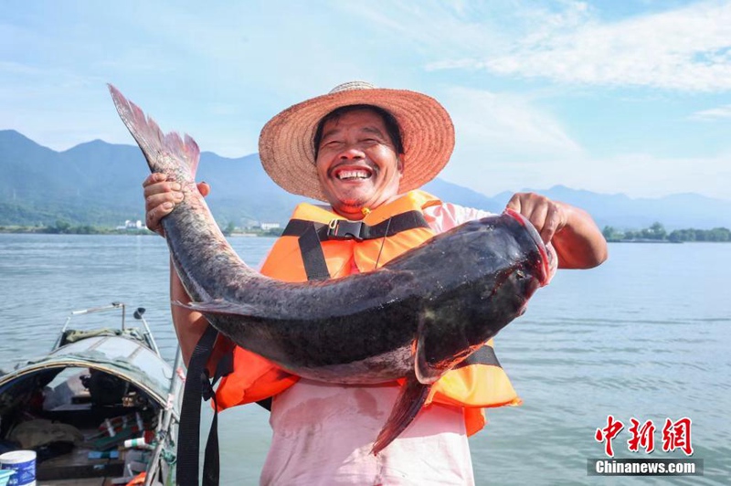 Mvuvi akiwa ameshikilia samaki aliyemvua kwenye Mto Fuchun, huko Hangzhou, Mkoa wa Zhejiang, China.