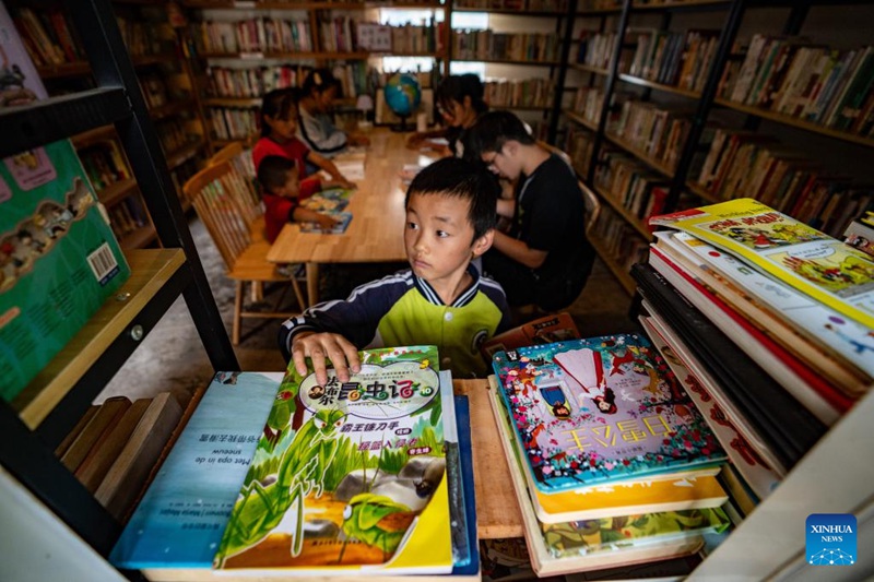 Mtoto akichagua vitabu kwenye maktaba ya "Banshan Huayu" katika Kijiji cha Qiunatong kilichoko Kitongoji cha Bingzhongluo katika Wilaya inayojiendesha ya kabila la Wadulong na kabila la Wanu ya Gongshan, Eneo linalojiendesha la kabila la Walisu la Nujiang, Mkoa wa Yunnan, Kusini-Magharibi mwa China, Julai 5, 2023. (Xinhua/Jiang Wenyao)