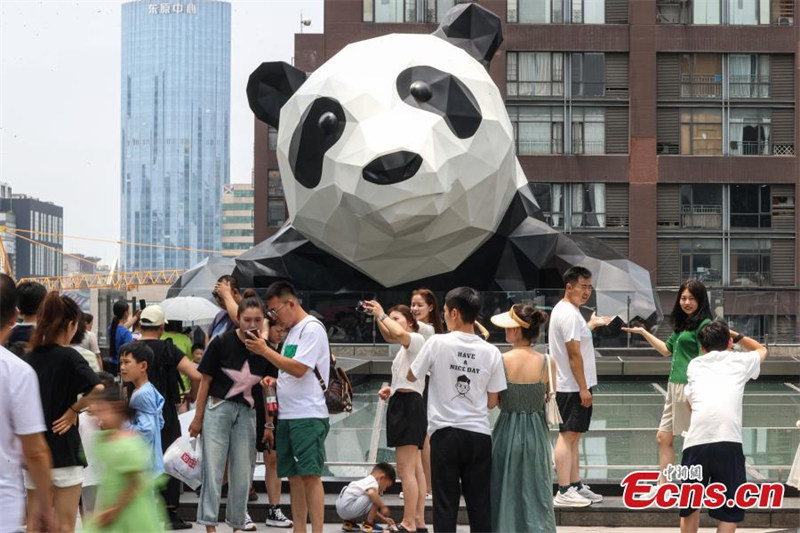 Tarehe 1, Agosti, 2023, watalii wakipiga picha pamoja na sanamu ya panda kwenye paa la jengo la IFS lililoko kiini cha Mji wa Chengdu wa Mkoa wa Sichuan, Kusini-Magharibi mwa China. (Picha ilipigwa na Qu Honglun/Chinanews)