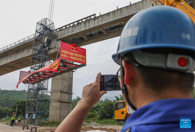 Mfanyakazi anapiga picha huku wenzake wakiweka reli ya mwisho yenye urefu wa mita 10 kwenye njia ya treni ya Maglev kwenye ujenzi wa njia hiyo yenye kasi ya kati na chini katika mji wa Qingyuan, Mkoani Guangdong kusini mwa China, Agosti 10, 2023. Mita hizo 10 zinaashiria kukamilika kwa kazi ya kuweka reli kwenye ujenzi wa njia hiyo mkoani Guangdong. (Xinhua/Liu Dawei)