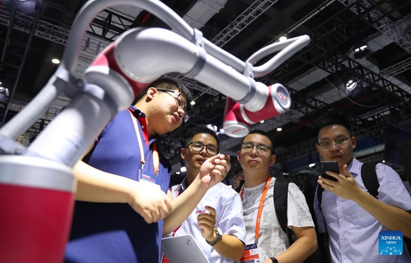 Mfanyakazi (kushoto) akizungumza na watembeleaji wa maonyesho pembeni mwa roboti kwenye Maonyesho ya 23 ya Viwanda ya Kimataifa ya China (CIIF) huko Shanghai, Mashariki mwa China, Septemba 19, 2023. (Xinhua/Fang Zhe)