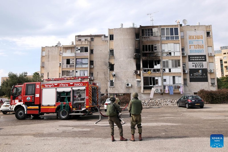 Picha iliyopigwa Oktoba 11, 2023 ikionyesha wanajeshi na gari la zimamoto likiwa mbele ya jengo lililobomolewa katika mashambulizi ya roketi kutoka Gaza, huko Ashkelon, Israel. (Ilan Assayag/JINI kupitia Xinhua)