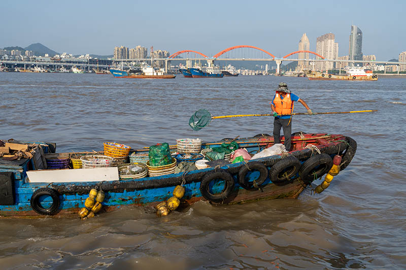 Mvuvi akikusanya takataka za baharini ili kuziweka wenye ngalawa ya kukusanya taka katika Gati la Yuncang lililoko Mji wa Zhoushan, Mkoa wa Zhejiang. (Chanzo cha picha: UNEP)