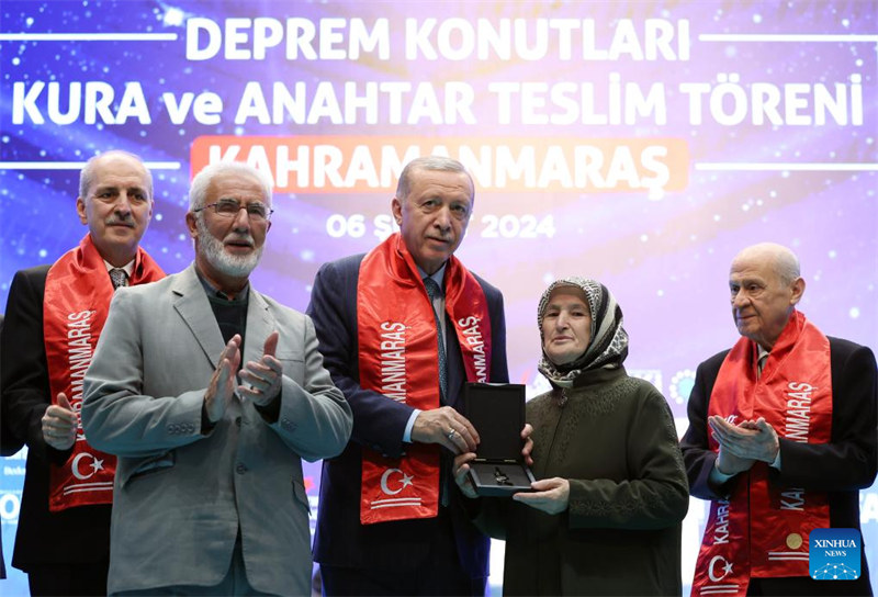 Rais wa Uturuki Recep Tayyip Erdogan (katikati) akikabidhi funguo ya nyumba kwa mwanamke kwenye hafla ya utoaji wa nyumba huko Kahramanmaras, Uturuki, Februari 6, 2024. (Picha na Mustafa Kaya/Xinhua)