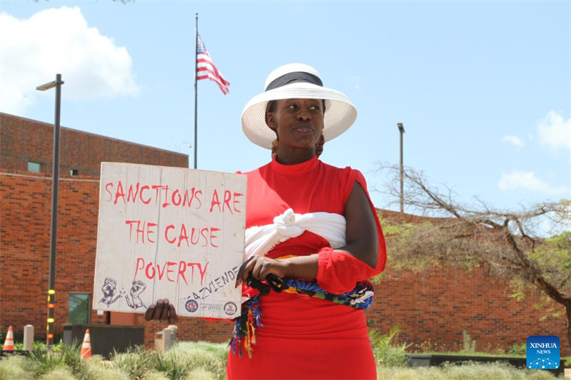 Mwanamke akiwa ameshikilia bango kupinga vikwazo vya Marekani mbele ya Ubalozi wa Marekani mjini Harare, Zimbabwe, Machi 5, 2024. (Picha na Tafara Mugwara/Xinhua)