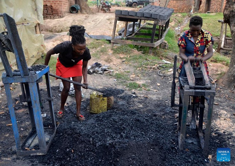 Sheeba Kwagala (Kulia) na mwenzake Shadia Abasa wakitumia vitu mbalimbali kutengeneza briketi kwenye kambi mjini Kampala, Uganda, Mei 30, 2024. (Picha na Nicholas Kajoba/Xinhua)