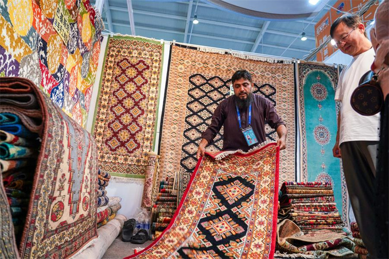 Muonyeshaji bidhaa wa Pakistan (Kushoto) akitambulisha zulia kwa watembeleaji maonyesho kwenye Banda la Asia Kusini katika Maonyesho ya 8 ya China na Nchi za Asia Kusini huko Kunming, Mkoa wa Yunnan, kusini-magharibi mwa China, Julai 26, 2024. (Xinhua/Wang Jingyi)