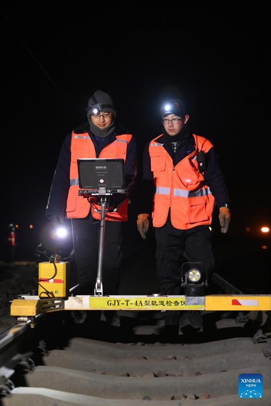 Wafanyakazi wa matengenezo Ma Xingshuo (kulia) na Cheng Xin wakiangalia reli katika Mji wa Lyuliang, Mkoa wa Shanxi, kaskazini mwa China, Januari 9, 2025. (Picha na Liu Liangliang/Xinhua)