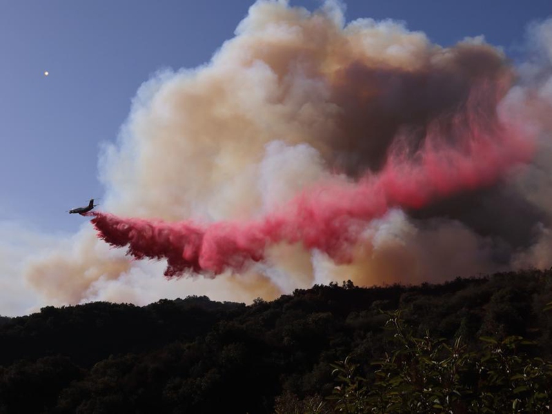 Ndege ya kuzima moto ikidondosha dawa za kuzima moto ili kuzuia moto wa nyika usienee zaidi kwenye vilima vya Mandeville Canyon mjini Los Angeles, California, Marekani, Januari 11, 2025. (Picha na Qiu Chen/Xinhua)