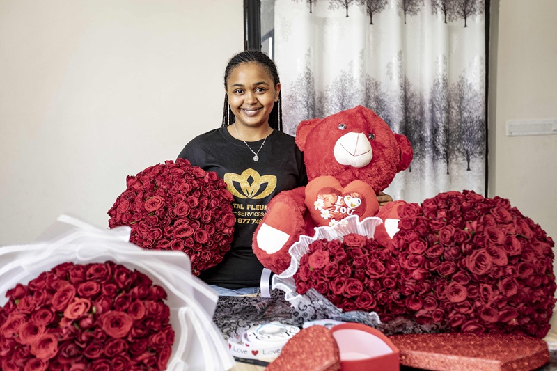 Mwenye duka akitabasamu huku akishika maua ya Siku ya Valentine huko Goma, DRC, Februari 13, 2025.