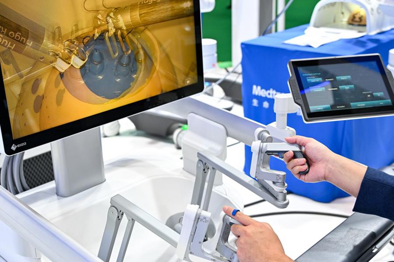 Mtembeleaji akijaribu roboti ya upasuaji kwenye banda la maonesho  ya Kampuni ya Medtronic katika Eneo la Maonyesho ya Vifaa Tiba na Bidhaa za Huduma za Afya kwenye Maonyesho ya 7 ya Kimataifa ya Uagizaji Bidhaa ya China (CIIE) mjini Shanghai, Mashariki mwa China, Novemba 5, 2024. (Xinhua/Zhang Cheng)