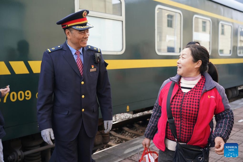 Xiang Baolin, Kondakta Mkuu wa treni Na. 6064 (kushoto), akizungumza na abiria nje ya Stesheni ya Reli ya Yanzibian katika Mkoa wa Shaanxi, kaskazini-magharibi mwa China, Februari 17, 2025. (Xinhua/Shao Rui)