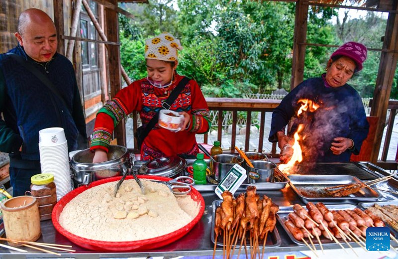 Wanakijiji wakiandaa mchele wa kunata na nyama ya nguruwe iliyochomwa kwa ajili ya watalii kwenye Kijiji cha Kabila la Wadong cha Zhaoxing katika Wilaya ya Liping ya Eneo linalojiendesha la Makabila ya Wamiao na Wadong la Qiandongnan, Mkoa wa Guizhou, kusini-magharibi mwa China, Machi 17, 2025.(Xinhua/Yang Wenbin)