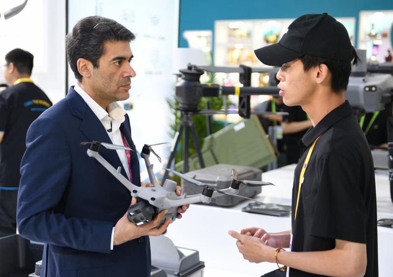 Mfanyakazi akitambulisha bidhaa kwa mgeni kwenye banda la DJI kwenye Maonesho ya 5 ya Bidhaa za Matumizi Duniani ya China  huko Haikou, Hainan, China, Aprili 15, 2025. (Xinhua/Sun Xiaotian)