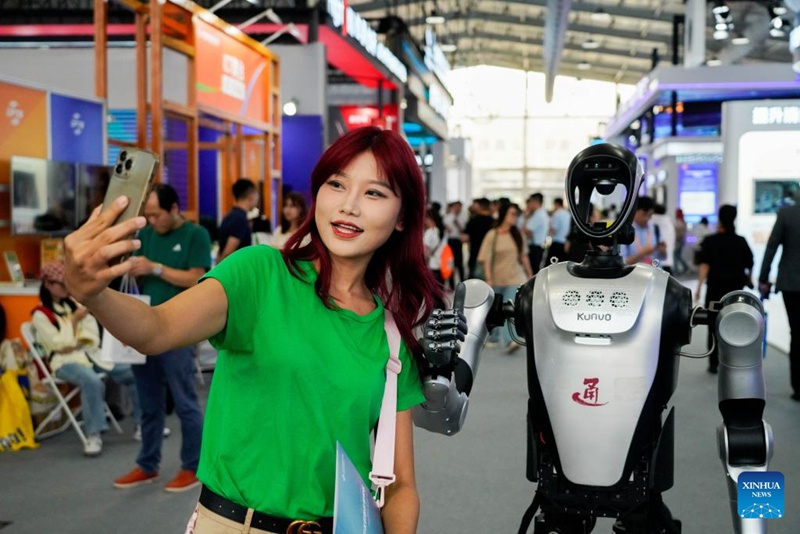 Mtembeleaji maonyesho akijipiga picha na roboti yenye muundo wa binadamu kwenye Maonyesho ya Kimataifa ya Biashara ya Huduma ya China 2025 (CIFTIS) mjini Beijing, mji mkuu wa China, Septemba 11, 2025. (Xinhua/Xie Han)