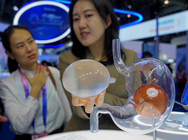 Mshiriki wa maonyesho akiuelezea mfumo wa puto la tumboni wa Orbera365, ambao hutumika kusaidia wagonjwa kupunguza uzito ya mwili kwenye eneo la maonyesho ya Vifaa vya Matibabu na Bidhaa za Kutunza Afya la Maonyesho ya nane ya Kimataifa ya Uagizaji Bidhaa ya China (CIIE) mjini Shanghai, mashariki mwa China, Novemba 6, 2025. (Xinhua/Liu Ying)