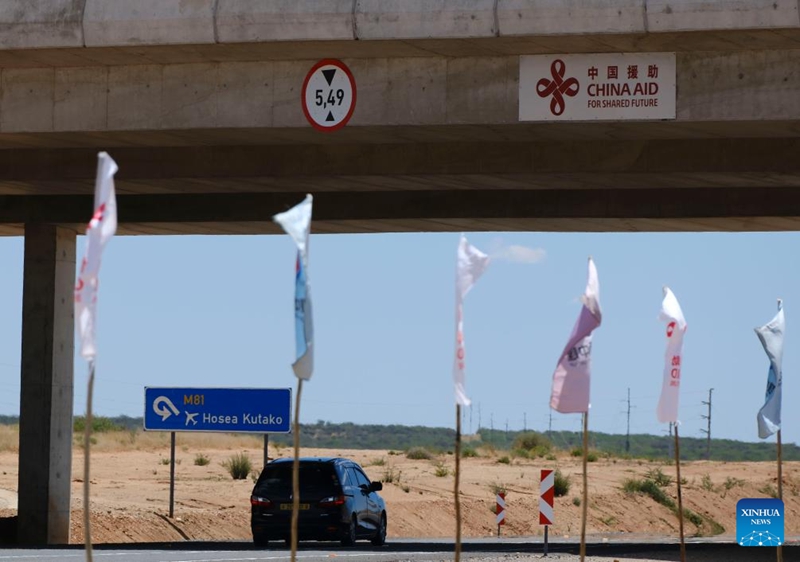 Gari likipita chini ya daraja lenye bango lenye maandishi "Msaada wa China" kwenye Barabara Kuu ya Dkt. Hage G. Geingob iliyojengwa kwa msaada wa China karibu na Windhoek, mji mkuu wa Namibia, Novemba 10, 2025. (Xinhua/Lin Jing)