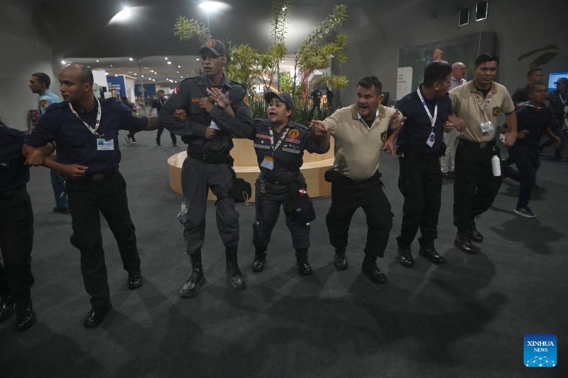 Wafanyakazi wa usalama wakiunda mnyororo wa binadamu kuongoza watu wanaokimbia kujiokoa kwenye eneo la Mkutano wa 30 wa Mabadiliko ya Tabianchi wa Umoja wa Mataifa (COP30) baada ya moto kuzuka mjini Belem, Jimbo la Para, Brazil, Novemba 20, 2025. (Picha na Lucio Tavora/Xinhua)