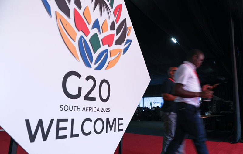 Watu wakitembea kuipita nembo ya Mkutano wa 20 wa Viongozi wa Kundi la 20 (G20) mjini Johannesburg, Afrika Kusini, Novemba 22, 2025. (Xinhua/Chen Wei)