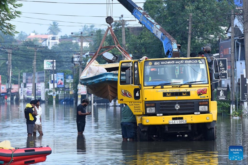 Mashua ya uokoaji ikisafirishwa kwa lori la kreni kupita mtaa uliofurika maji mjini Colombo, Sri Lanka, Desemba 1, 2025. (Picha na Gayan Sameera/Xinhua)