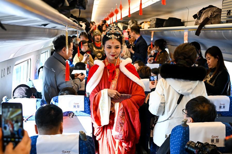 Mfanyakazi (katikati) akiwasiliana na abiria ndani ya treni ya mwendokasi No. D4667, Desemba 23, 2025. (Xinhua/Li Zhipeng)