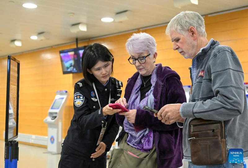 Afisa wa polisi wa ukaguzi wa mpakani akiwasaidia watalii wa kigeni kujaza taarifa za kuingia katika Uwanja wa Ndege wa Kimataifa wa Pudong wa Shanghai, mashariki mwa China, Februari 11, 2026. (Xinhua/Chen Haoming)