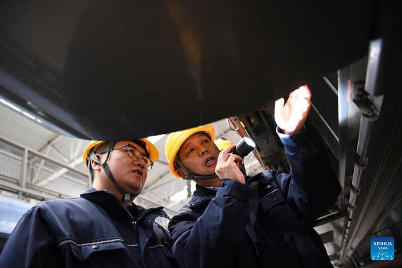 Dong Hongtao (kulia) na mfanyakazi mwenzake wakikagua na kuifanyia matengenezo treni ya mwendo-kasi kwenye karakana ya matengenezo ya Kampuni ya Kundi la Reli la Xi’an la China,  katika Mkoa wa Shaanxi, kaskazini magharibi mwa China, Januari 14, 2026. (Xinhua/Li Yibo)