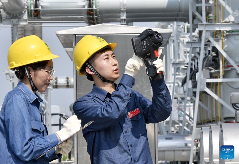 Wafanyakazi wa Kampuni ya Beijing ya Shirika la Gridi ya Kitaifa wakikagua kifaa cha umeme kwa kipimajoto cha infrared kwenye kituo kidogo cha kupozea umeme wa kV 500, mjini Beijing, Agosti 6, 2026. (Picha na Zhang Xiaotan/Xinhua)