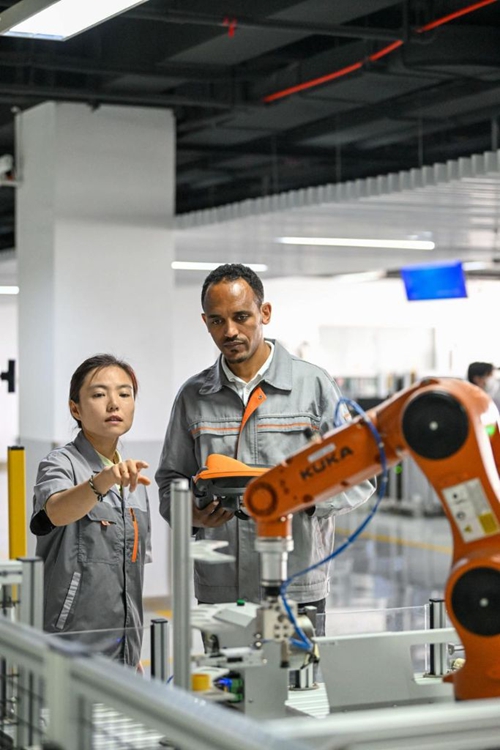 Tola Tsegaye Alemu (Kulia) kutoka Ethiopia akiendesha roboti ya viwandani chini ya mwongozo wa mwalimu katika Chuo Kikuu cha Teknolojia na Elimu cha Tianjin kaskazini mwa China. Tianjin, Juni 27, 2024. (Xinhua/Sun Fanyue)