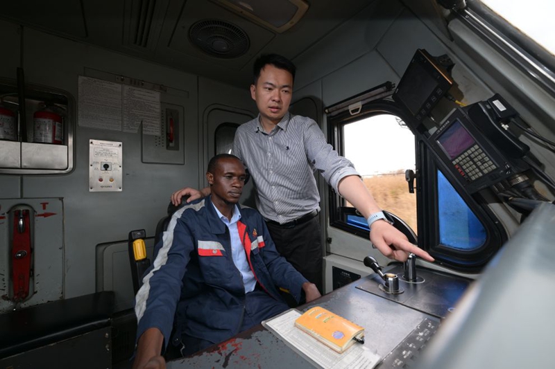 Mhandisi wa mawasiliano Zhou Junbing (kulia) akizungumza na dereva wa treni Mkenya ndani ya treni inayoelekea Mombasa kwenye Reli ya SGR ya Mombasa-Nairobi, nchini Kenya, Julai 23, 2026. (Xinhua/Yang Guang)
